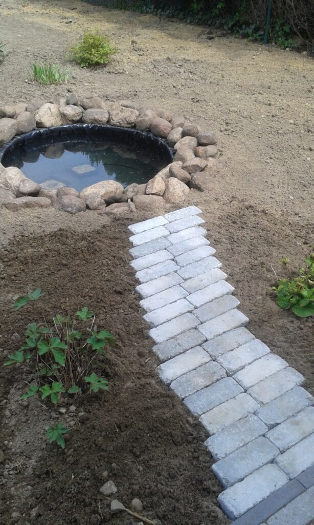 Um den Trecker-Reifen wurden noch Feldsteine gelegt und ein kleiner Weg aus den Resten der Pflasterung gelegt.